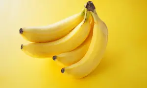Pęczek żółtych bananów na żółtym tle. Idealna przekąska, gdy zastanawiasz się nad banan kalorie.
