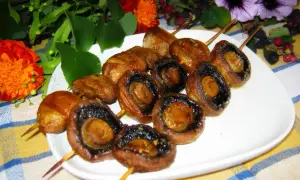 Pieczarki na patyczkach, idealne do grillowania, pokryte aromatyczną marynatą.