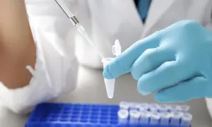 Ręka w niebieskiej rękawiczce laboratoryjnej używa pipety do pobrania płynu z probówki.