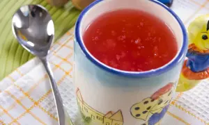 Czerwony kisiel w kubeczku z bajkowym wzorem, obok łyżeczka. Idealny deser, gdy liczymy kisiel kcal.