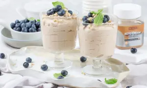 Dwa pucharki z kremowym, szybkim deserem z mascarpone keto, udekorowane borówkami i miętą.