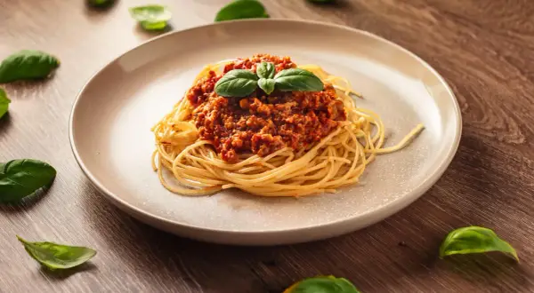 Pyszne spaghetti bolognese, idealne na prosty obiad. Aromatyczny sos mięsny z pomidorami i świeża bazylia na makaronie.
