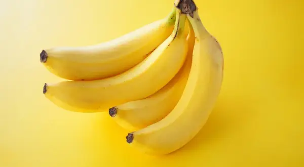Pęczek żółtych bananów na żółtym tle. Idealna przekąska, gdy zastanawiasz się nad banan kalorie.