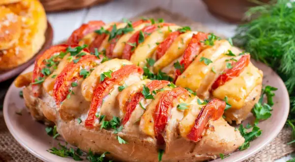 Pyszne pieczone piersi z kurczaka z pomidorami i serem, posypane natką pietruszki. Idealne co na obiad z kurczaka!
