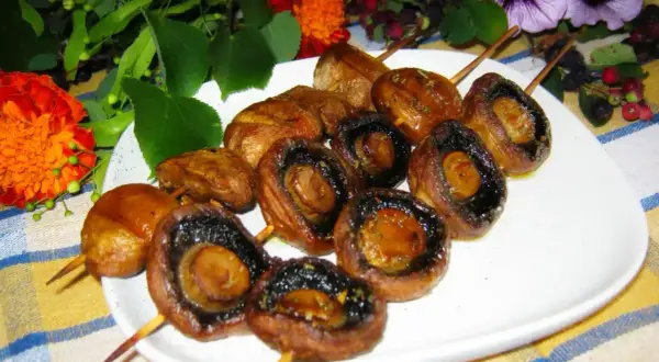 Pieczarki na patyczkach, idealne do grillowania, pokryte aromatyczną marynatą.