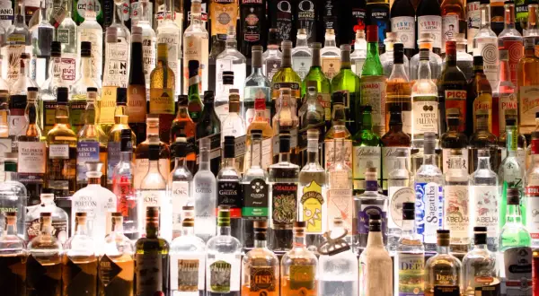 Wiele butelek alkoholu na półce. Szukając, jaki alkohol ma najmniej kalorii, warto zwrócić uwagę na te przejrzyste.