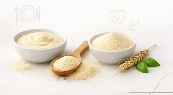 Dwie miseczki z kaszą manną, jedna gotowa, druga sucha. Łyżka z suchą kaszą. Kłos zboża i liście. Czy kasza manna ma gluten? Tak, jest z pszenicy.