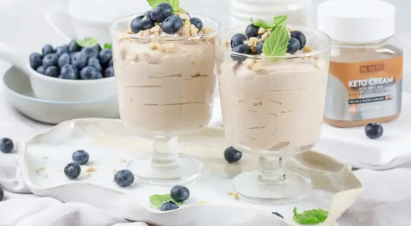Dwa pucharki z kremowym, szybkim deserem z mascarpone keto, udekorowane borówkami i miętą.