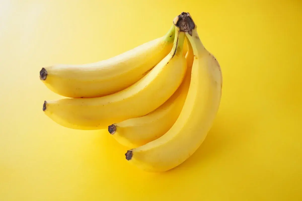 Pęczek żółtych bananów na żółtym tle. Idealna przekąska, gdy zastanawiasz się nad banan kalorie.