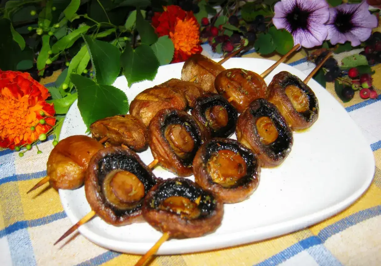 Pieczarki na patyczkach, idealne do grillowania, pokryte aromatyczną marynatą.