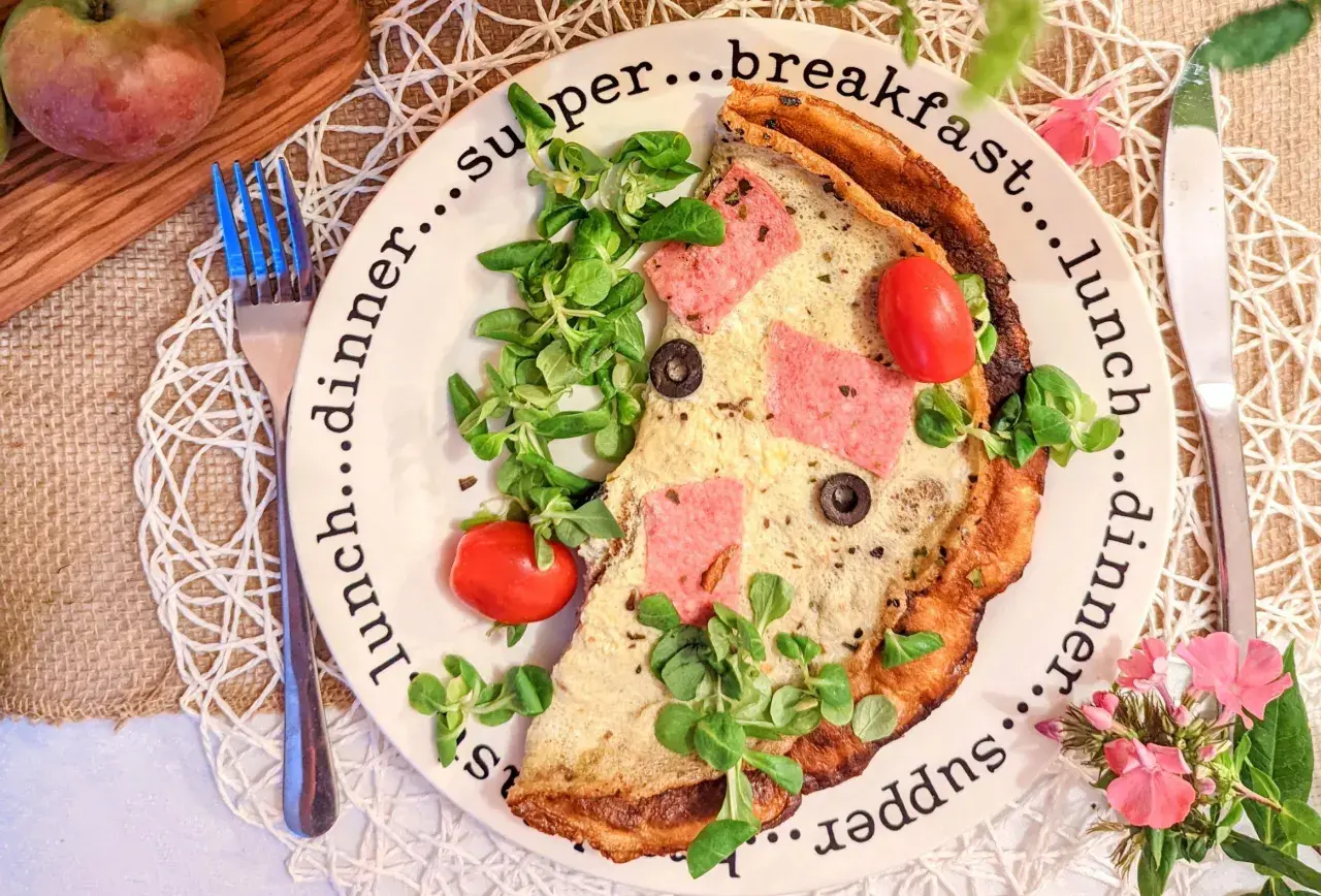 Omlet z szynką, pomidorkami i rukolą na talerzu z napisami "breakfast", "lunch", "dinner", "supper".