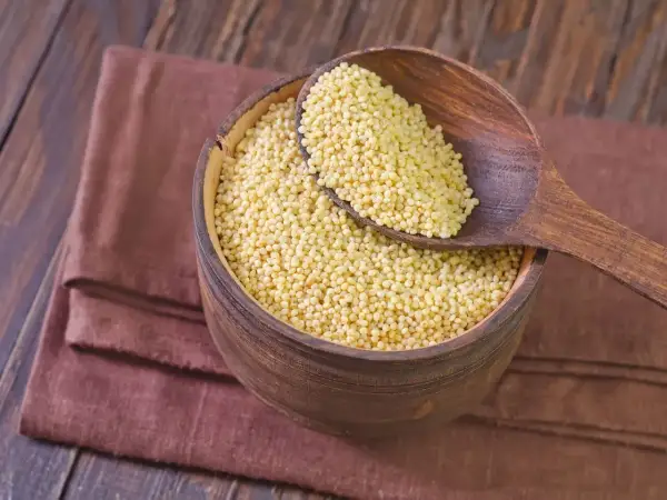 Kasza jaglana w drewnianej misce i łyżce. Czy kasza jęczmienna ma gluten? Jaglana jest bezglutenowa.